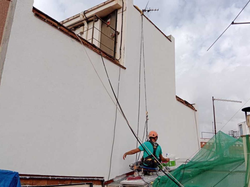 Hermes Vertical obrero subido en tejado rehabilitando fachada