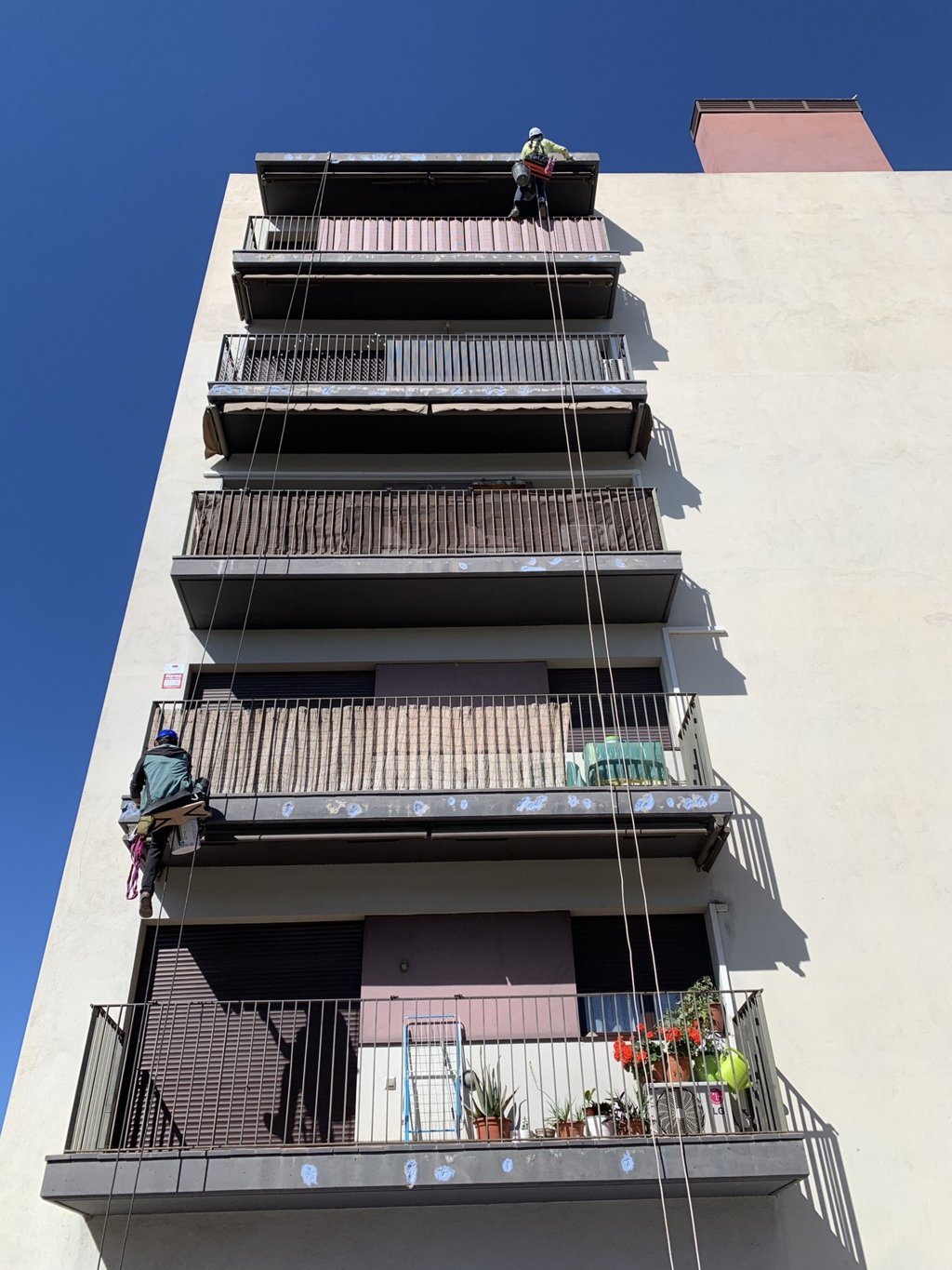 Hermes Vertical vista de edificio con cuerdas con obreros subidos